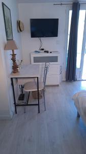 a room with a table and a desk with a television at Ecolieu La pépinière in Carnoux