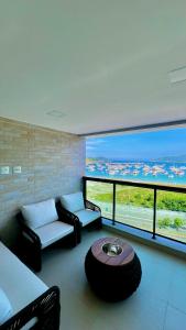 Una sala de estar con un sofá y una ventana grande. en Apartamento 3 suítes Vista Mar Praia do Anjos - Arraial, en Arraial do Cabo