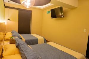 a hotel room with two beds and a tv at Hotel Casa Tsumbak in Tuxtla Gutiérrez
