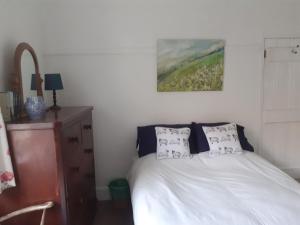 a bedroom with a bed and a painting on the wall at Robert's Cottage in Abergynolwyn