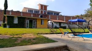 un gruppo di sedie seduti di fronte a una casa di Finca 7 Reyes Casa con alberca a Villa del Carbón