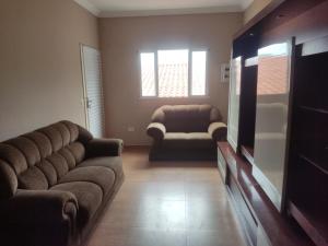 Una sala de estar con un sofá y un televisor. en Cobertura em quintal compartilhado, en Suzano