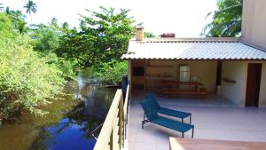 ein Haus mit zwei Stühlen auf einem Balkon neben einem Fluss in der Unterkunft Villa Colibri Barra de São Miguel. in Barra de São Miguel