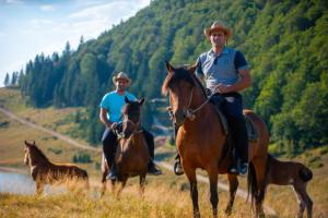 two men are riding horses in a field at Katun Siska Medna Dolina in Berane
