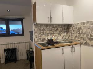 uma cozinha com armários brancos e uma pia em Vuk & Sofija Apartmani em Kopaonik