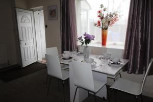 a white dining room table with white chairs and flowers at Richmond House in Sheffield