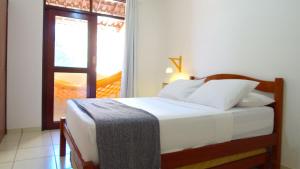 Schlafzimmer mit einem Bett und einem Fenster mit einer Tür in der Unterkunft Villa Colibri Barra de São Miguel. in Barra de São Miguel