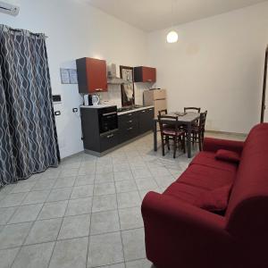 Una sala de estar con un sofá rojo y una cocina. en Sardinia House Country, en SantʼAnna Arresi 10 fotos más