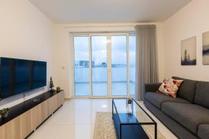 a living room with a couch and a large window at Beautiful Central Penthouse 1br in Taʼ Xbiex