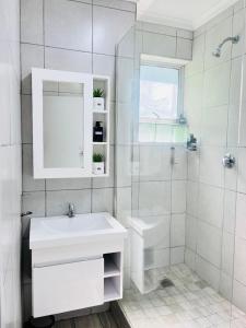 a white bathroom with a sink and a shower at Durban Beachfront Bliss in Durban
