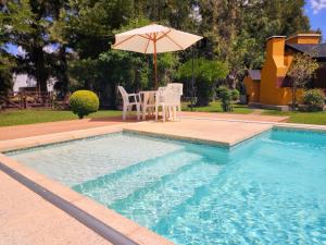 - une piscine avec une table, un parasol et des chaises dans l'établissement Casa quinta en Brandsen, à Brandsen