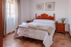 een slaapkamer met een groot bed met een houten hoofdeinde bij Casa rural con piscina, barbacoa, aire acondicionado, WiFi de alta velocidad, cocina exterior y Parking in Córdoba