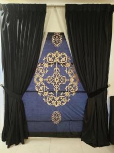 a bed with black curtains and a blue and gold bedspread at Zameen Opal in Lahore +3 photos