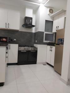 a kitchen with white cabinets and black appliances at Zameen Opal in Lahore