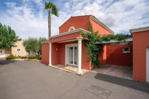 a red house with a palm tree behind it at Villa Avec Piscine partagée in Cap d'Agde
