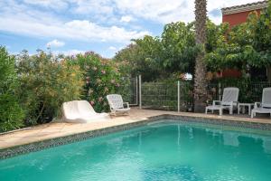 een zwembad met 2 ligstoelen en adozen bij Villa Avec Piscine partagée in Cap d'Agde