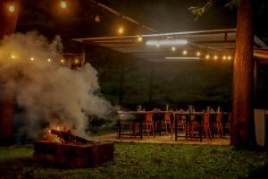 a grill with a table and chairs next to a fire at Shola Gardens , Kotagiri in Kotagiri