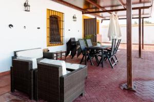 een terras met een tafel, stoelen en een parasol bij Casa rural con piscina, barbacoa, aire acondicionado, WiFi de alta velocidad, cocina exterior y Parking in Córdoba