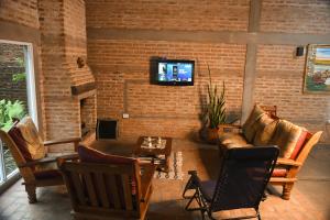 sala de estar con sofá y TV en una pared de ladrillo en LORETO GUEST HOUSE YAYETOPa, en Loreto