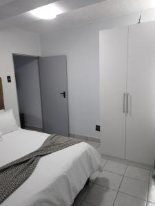 1 dormitorio con 1 cama y armarios blancos en Grace Villas 6, en East London