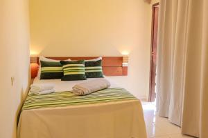 Schlafzimmer mit einem Bett mit grünen und weißen Kissen in der Unterkunft Kanoas Suites in São José da Coroa Grande