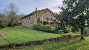 an old stone house with a grassy yard at Casa Bezales en Ampuero Cantabria in Ampuero