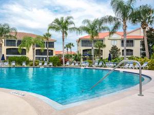 a large swimming pool with chairs and palm trees at Pet Friendly Bouchelle Island Condo! Walk out sliders to the Pool - BO302 - 103 in New Smyrna Beach