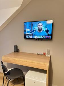 einen TV an einer Wand mit einem Tisch und einem Stuhl in der Unterkunft Chambre privée "Graine de Coton" - Cuisine partagée in Amiens + 9 Fotos