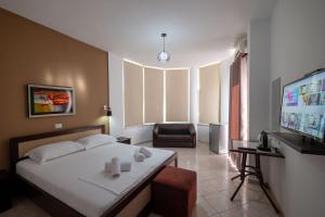 a bedroom with a bed and a chair and a television at Mariksel HOTEL in Ksamil