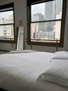 a bedroom with a white bed and two windows at Historic Downtown LA Loft - Urban Charm in Los Angeles