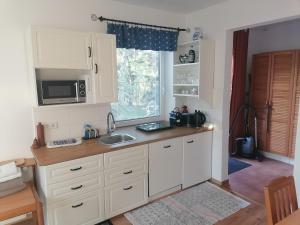 a kitchen with white cabinets and a sink and a window at Gartenapartment Storchenblick in Weiden am See