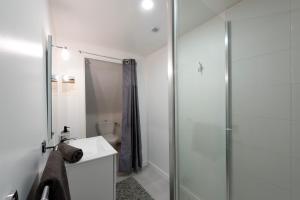 een witte badkamer met douche en wastafel bij Le Coquet in Lannion