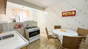 a kitchen with a table and a stove and a sink at 200 metros da Praia Central na Avenida Brasil próximo à Roda Gigante e Shopping Atlântico in Balneário Camboriú