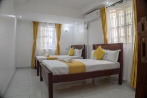 two beds in a room with yellow curtains at Leah's Luxury Villa in Mombasa