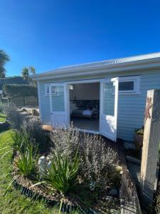 a blue house with a door open in a yard at The Shack in Christchurch