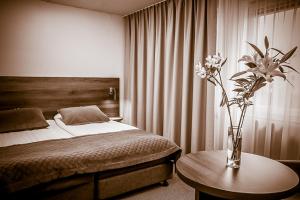 Un dormitorio con una cama y una mesa con un jarrón de flores en Hotell Nivå, en Boden