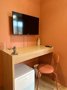 a desk with a television on a wall with a chair at Chambre privée "Nuage du matin" - Cuisine partagée in Amiens +3 photos
