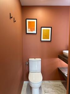 a bathroom with a toilet and two pictures on the wall at Chambre privée "Nuage du matin" - Cuisine partagée in Amiens