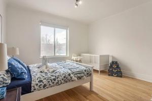 a white bedroom with a bed and a window at Charm & Luxury Vacation Headquarters to Downtown! in Montréal