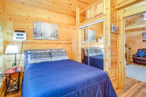 1 dormitorio con 1 cama azul en una cabaña de madera en Grill, Fire Pit Pet-Friendly Lakeside Cottage!, en Lake of the Woods