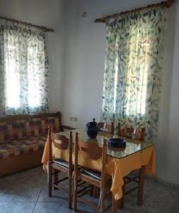 a dining room with a table and chairs and windows at A CASA D'IRENE in Votsalákia