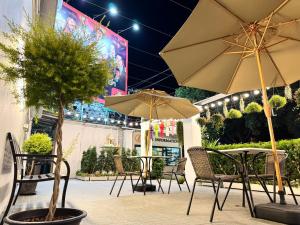 チェンマイにあるNidhra Lanna Hotel Chiang Maiのテーブル、椅子、パラソルのある屋外パティオ