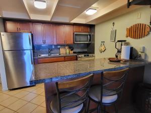 a kitchen with a stainless steel refrigerator and two bar stools at Molokai Kepuhi Beach Gem in Kepuhi