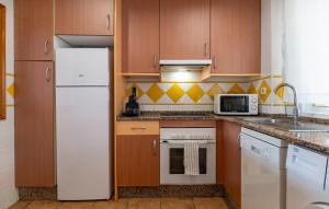 La cuisine est équipée d'un réfrigérateur blanc et d'un four micro-ondes. dans l'établissement 2 Bedroom Nice Apartment In Puerto Rey, à Media Legua