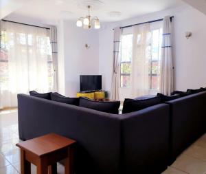 ein Wohnzimmer mit einem großen Sofa und einem Fernseher in der Unterkunft Mara Home 2 in Arusha