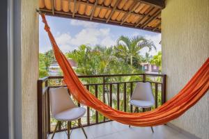 a hammock on a balcony with two chairs and palm trees at Flat Solar Água- by Pipa Praia House in Pipa