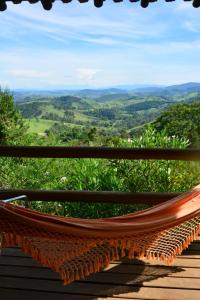 a hammock on a deck with a view of the mountains at Pousada Quinta da Serra in Cunha