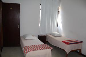 una camera con due letti e una panca di Hotel Aquarius a Coronel Fabriciano