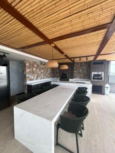 cocina grande con encimera blanca grande y sillas en Flat makani carneiros tamandare, en Tamandaré