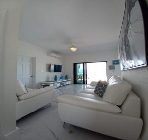 a white living room with two white couches at Las Brisas Azules in Providenciales